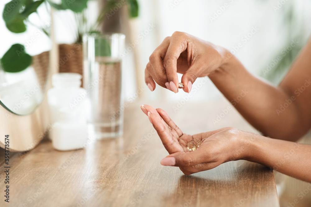 Professional-grade supplement capsules and a glass of water on a beige background